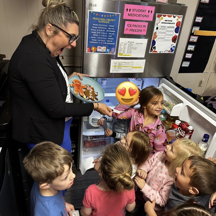 group of preschoolers standing around a smiling woman in front of an open fridge