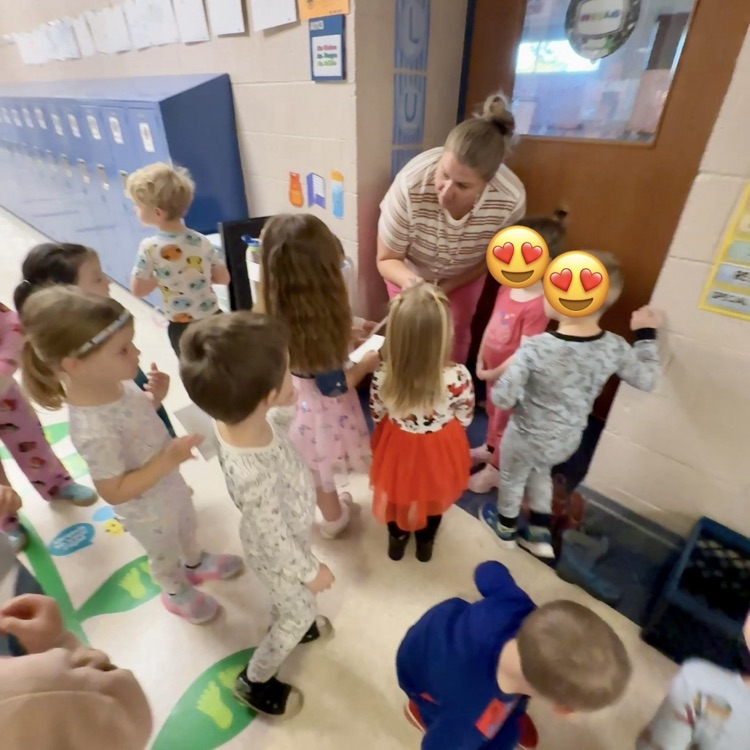 group of preschoolers standing outside a classroom with a teacher
