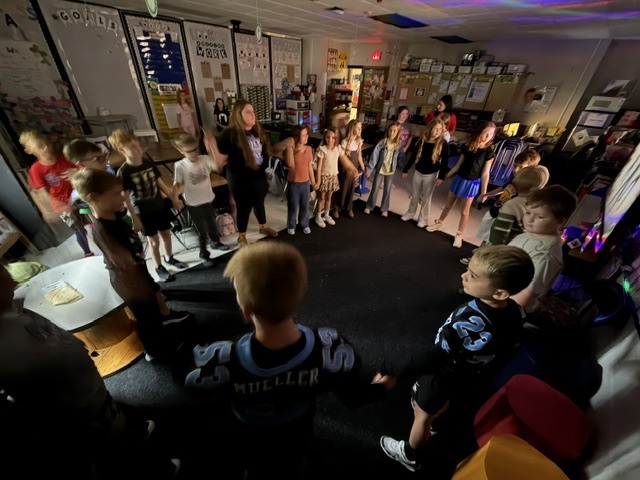 class standing in a circle in a classroom