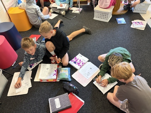 4 students doing homework on the floor in a classroom