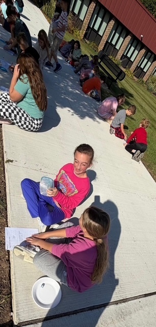 2 girls sitting outside doing schoolwork