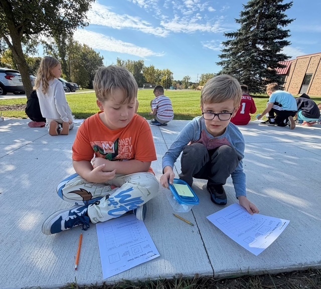 2 boys sitting outside doing schoolwork