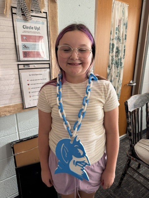 girl smiling wearing a blue devil on a necklace