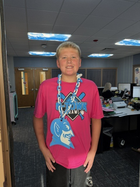 boy smiling wearing a blue devil on a necklace