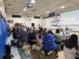 group of adults sitting together at tables in a gym