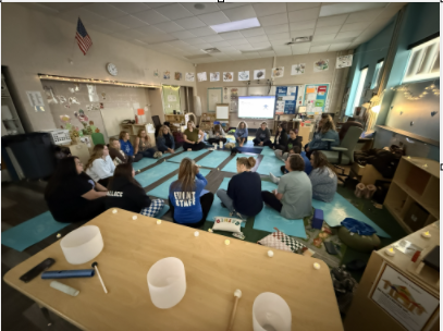 group of teachers sitting in a circle in a classroom