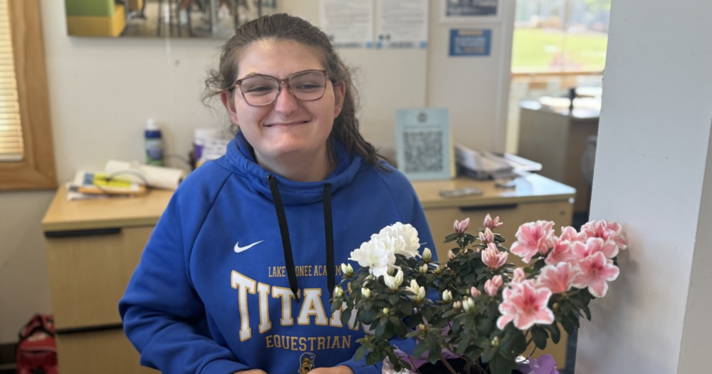 student in HS with Flowers on desk.