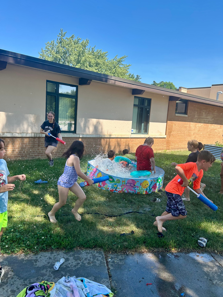 kids playing outside in grass with hose and kiddie pool