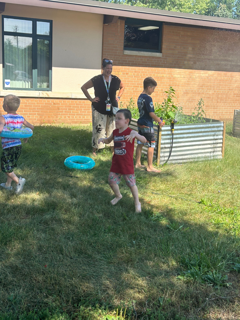 kids playing outside in grass with hose