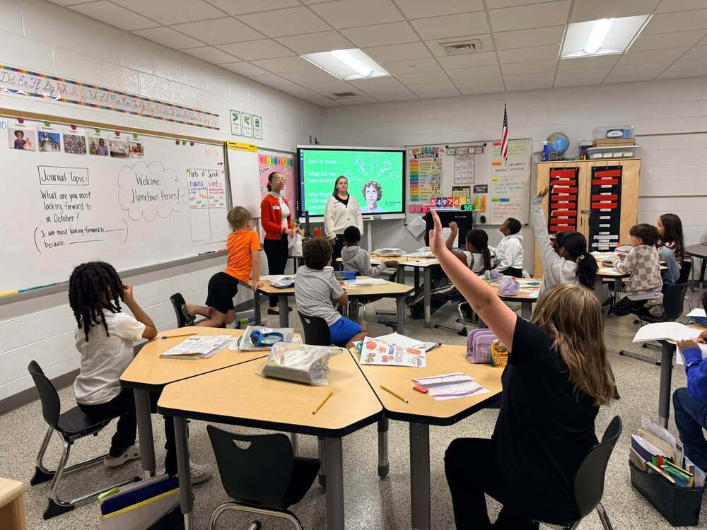LES students in a 3rd grade classroom raising their hand getting ready to ask the Blue Rdige Bank workers a question