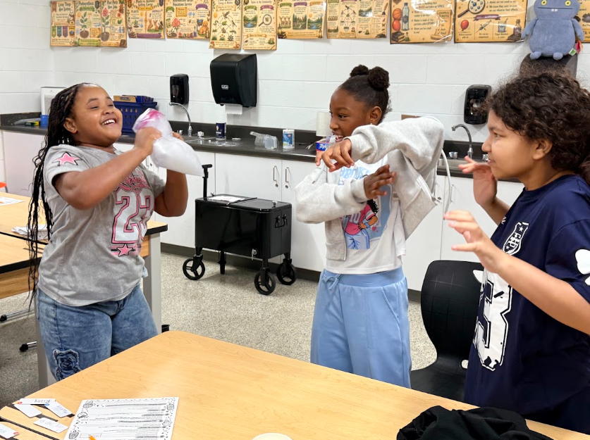 5th graders shaking a bag to investigate how thermal energy transforms coffee creamer into ice cream