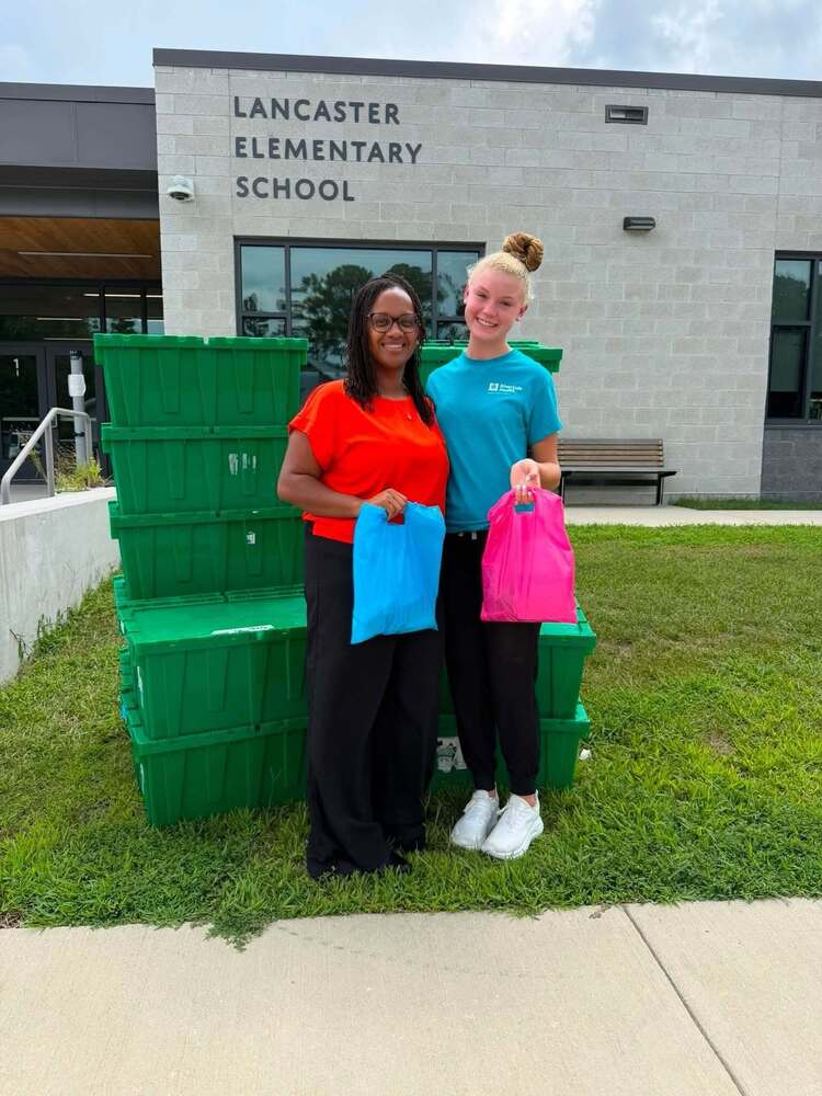 Principal Kenner and Miss Horn of Fresh Start standing in front of LES with hygiene bags.
