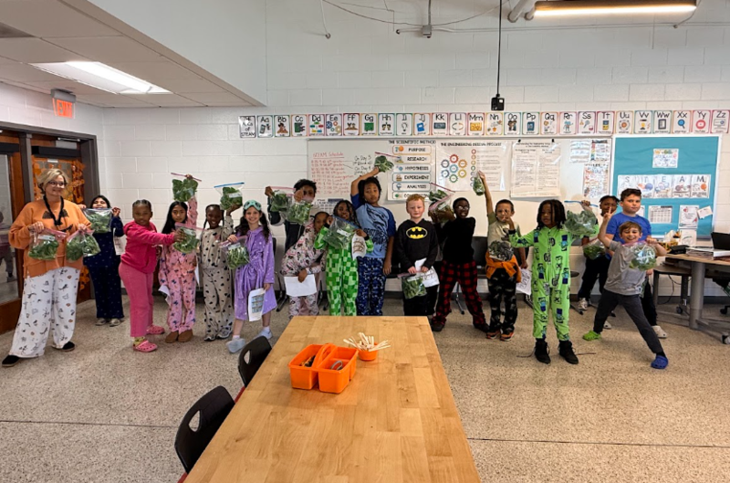 Mrs. Fisher's class in Mrs. McCranie's STEAM classroom holding up bags of lettuce that they harvested!