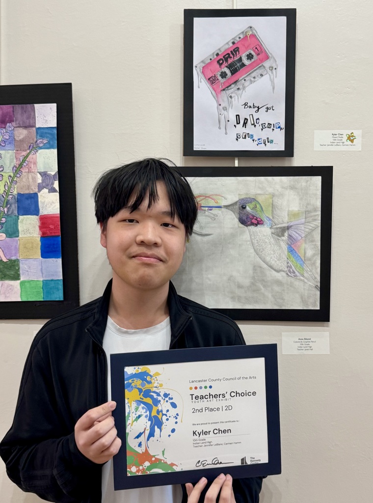 Kyler C. with his certificate in front of his artwork