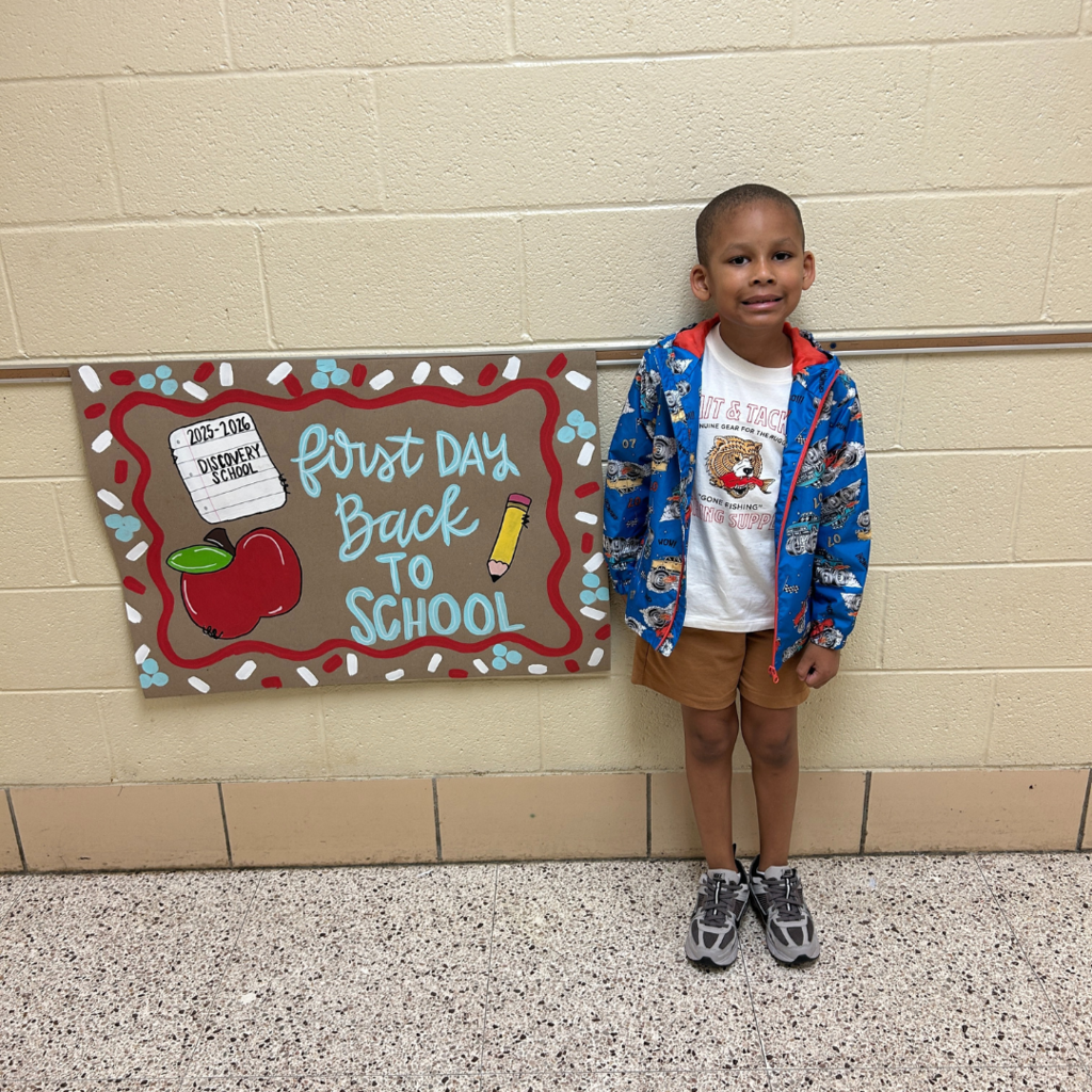 student standing next to first day back picture