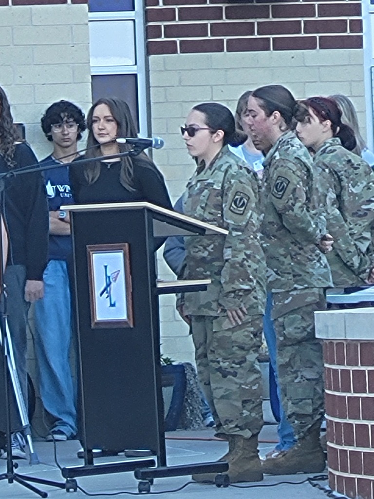 Nicole A stands at podium, speaking as Mistress of Ceremony 