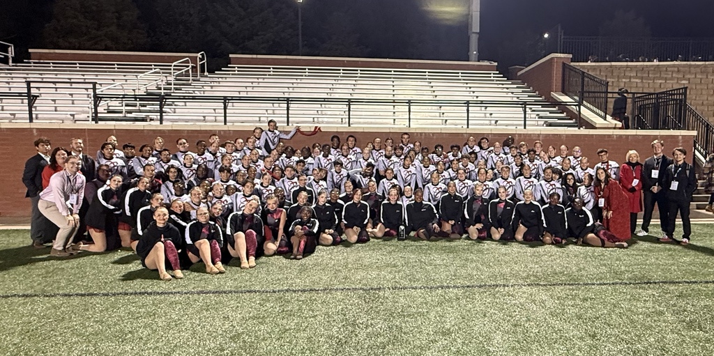 Indian Land High school Marching Band and Color Guard, poses in front of the bleachers on the field in their uniforms