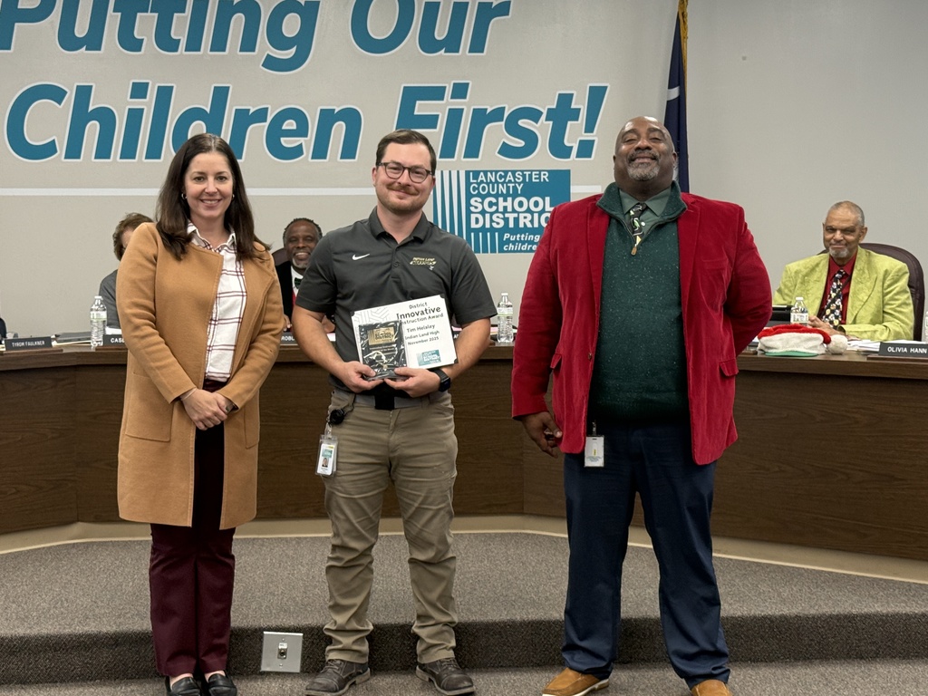 ILHS AP, Ms. Merril, ILHS teacher Mr Hensley, and LCSD Superintendent Mr. Fitzpatrick stand in front of LCSD board room with award plaque 