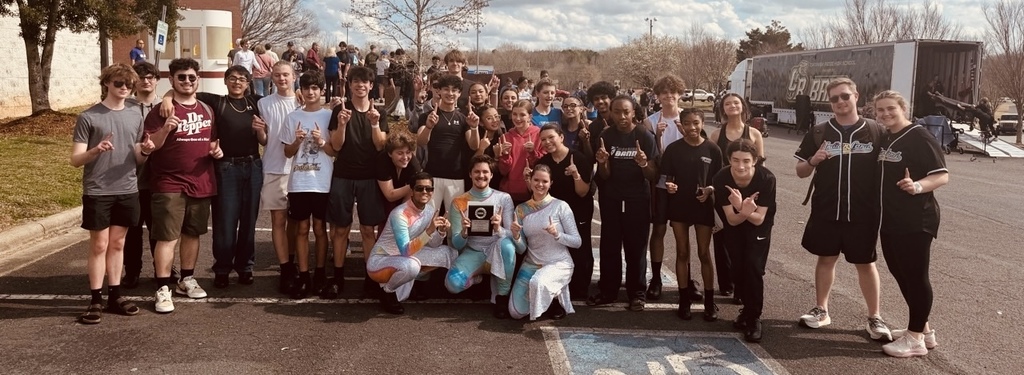 color guard and percussion group poses outside, holding their award
