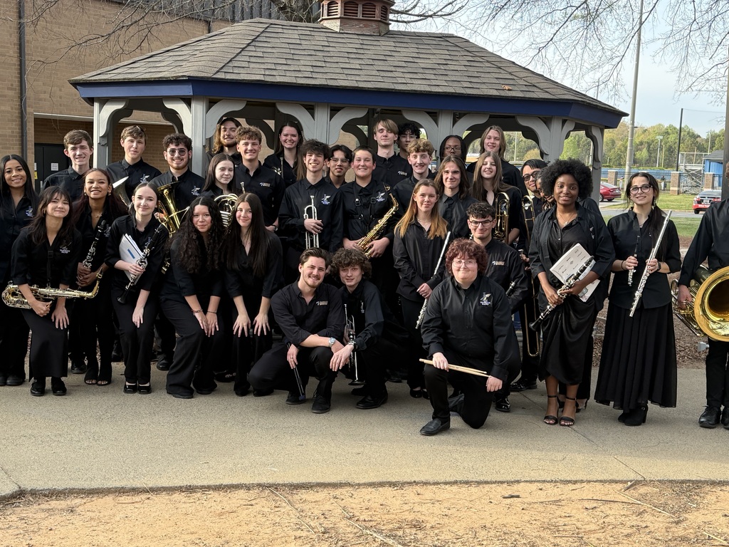 band members dressed in concert blacks pose with their instruments after a successful performance. 
