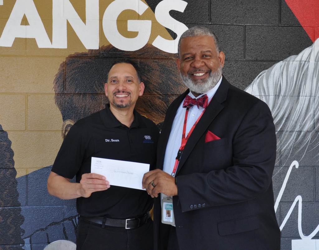 Photo of Principal Chavous receiving winnings check from Dr. Murdock.