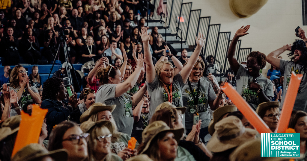 An audience in a stadium, some cheering, wearing hats and gray shirts. Bright colors and shadows.