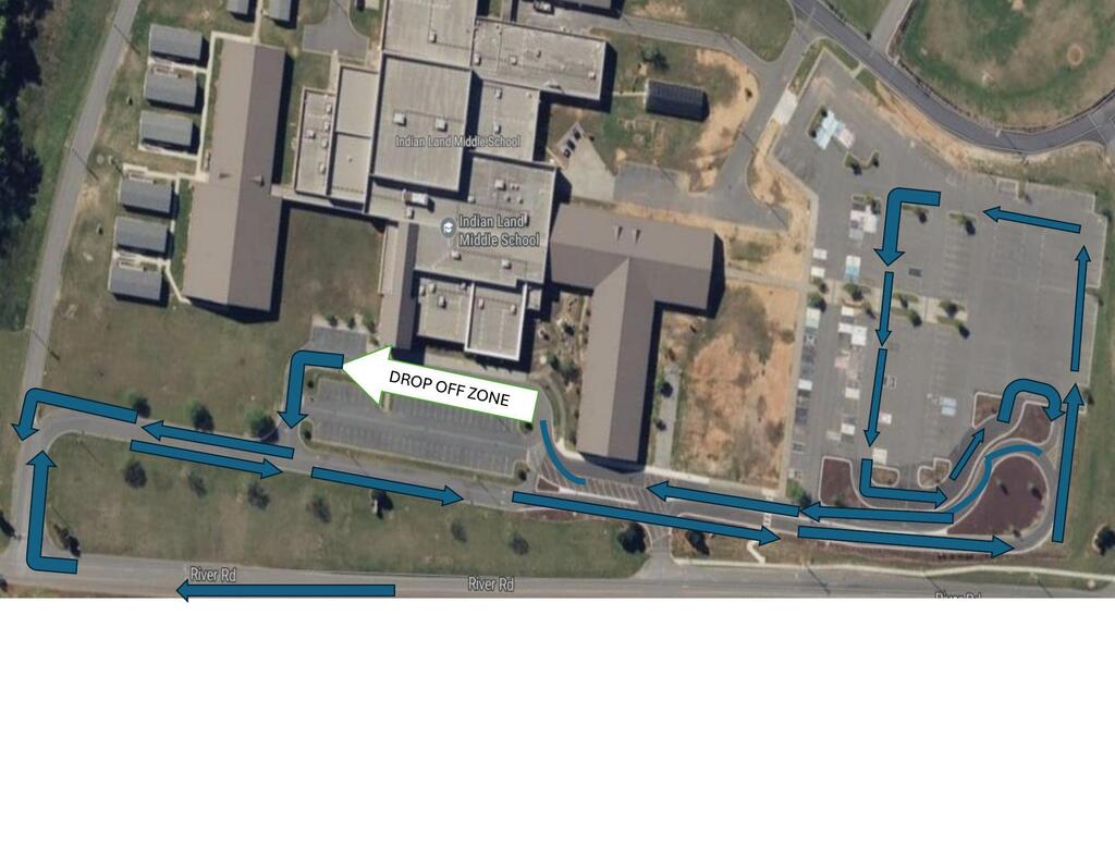 An aerial view of a school with a marked drop-off zone, parking lot, and surrounding greenery.