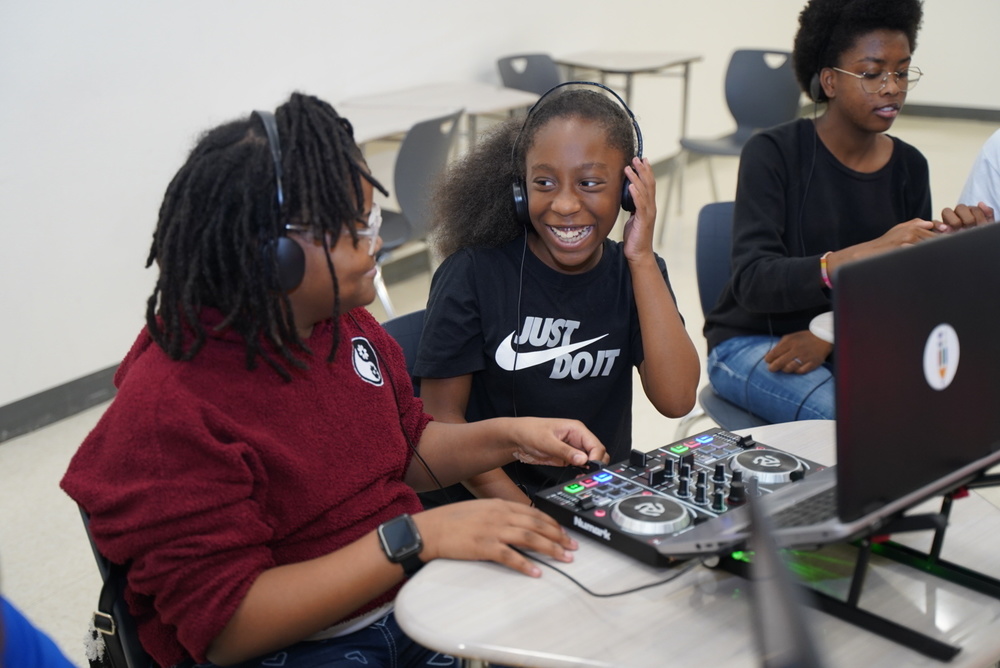 Students smile and play with DJ equipment