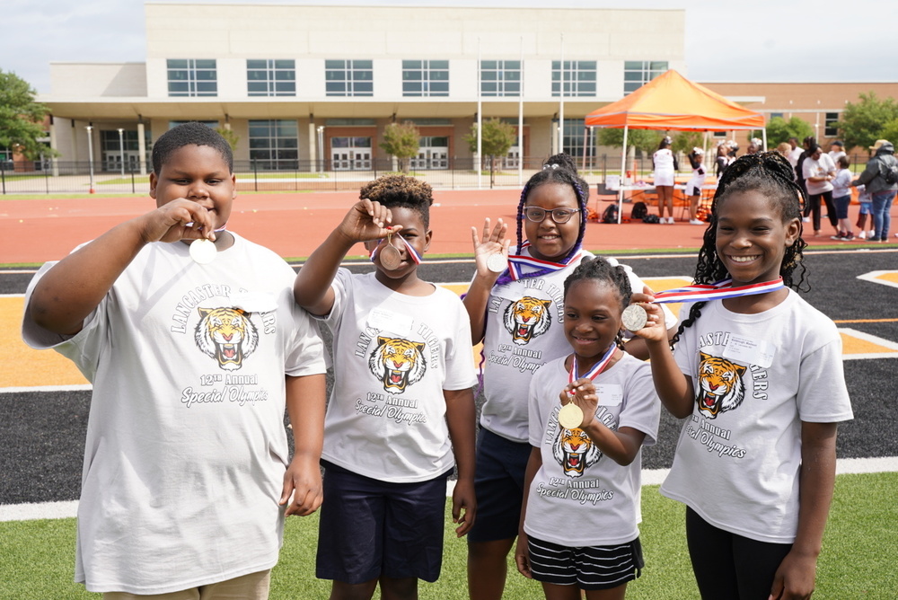 Students stand holding medals