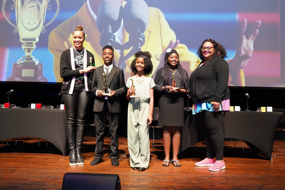 Three students and two staff members pose after receiving trophies