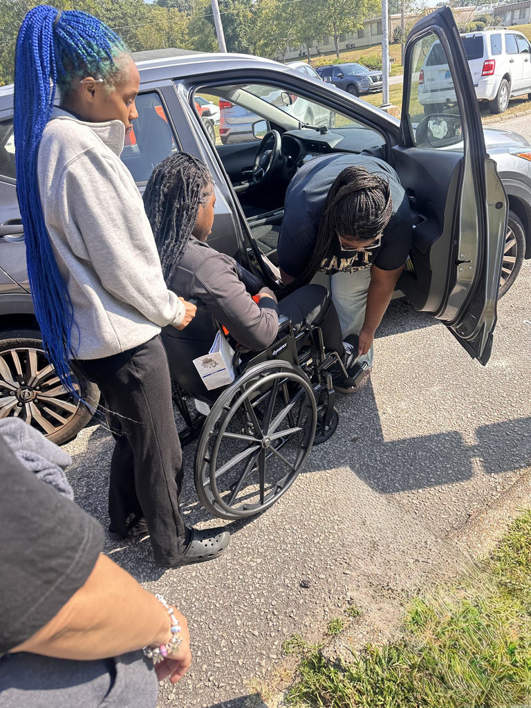 Students in the Patient Care Technician Class are learning to transfer a person from a wheelchair to a car. 