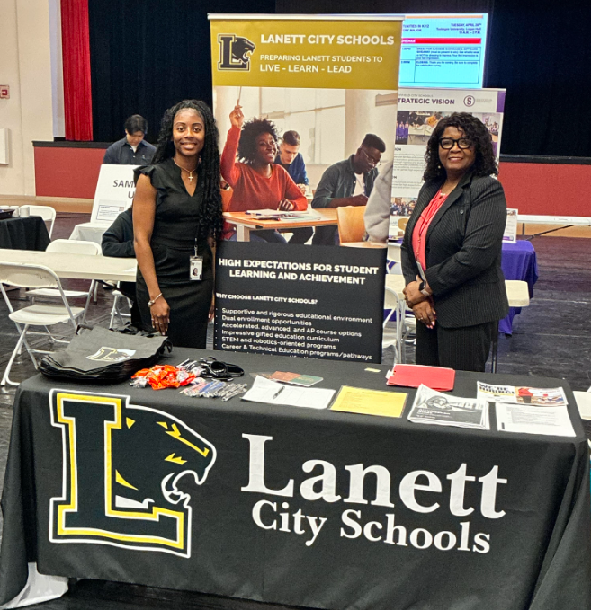 Picture of Ms. Carlisle and Ms Staples at the career fair.  The table has text that says Lanett City Schools. 