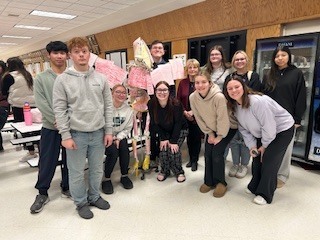 Mrs. Hope's group-A group of students standing together in a school hallway , wearing casual clothing and backpacks.