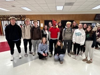 Mrs. Sander's group- A group of students standing together in a school hallway , wearing casual clothing and backpacks.