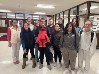 Mrs. Hart's group-A group of students standing together in a school hallway with offices behind them, wearing casual clothing and backpacks.