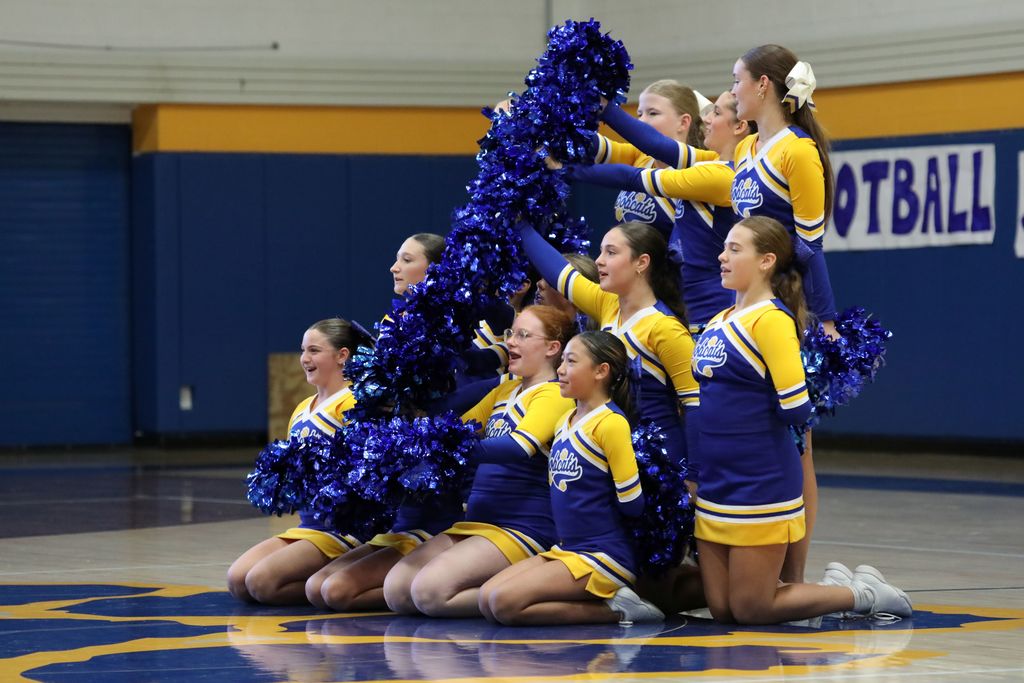 cheerleaders gathered in a small grouping and holding up pom poms 