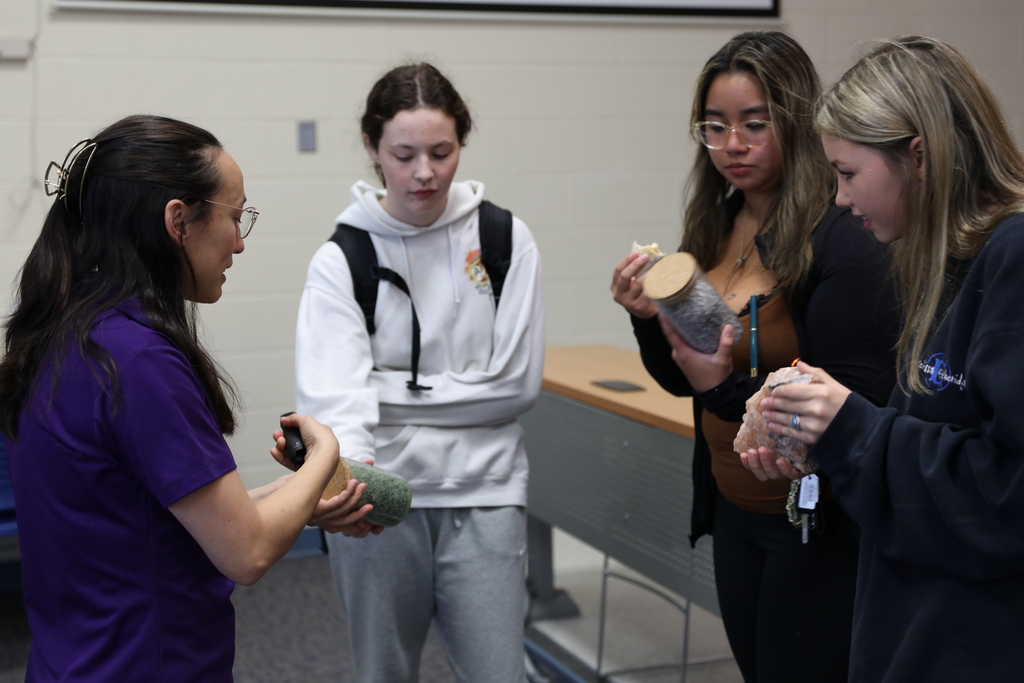 three students being shown salt in a jar