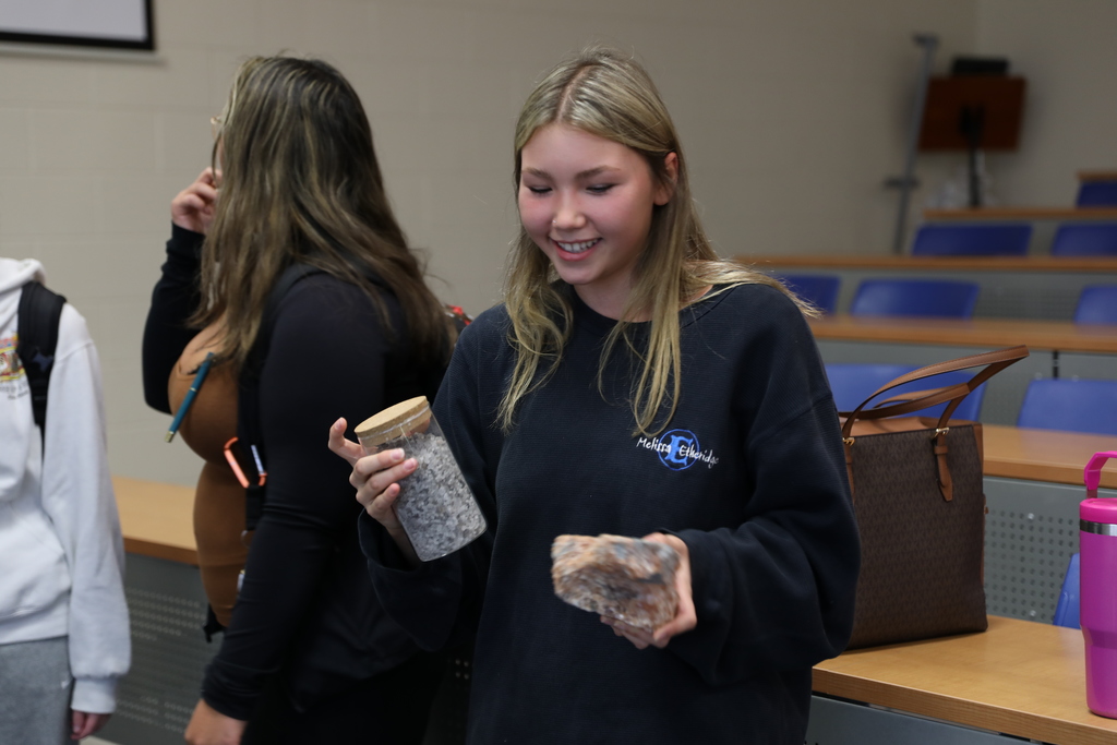 A student looking at a large solid piece of salt from the mine and also a jar of crushed road salt