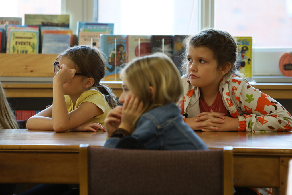 three students listening to an author 