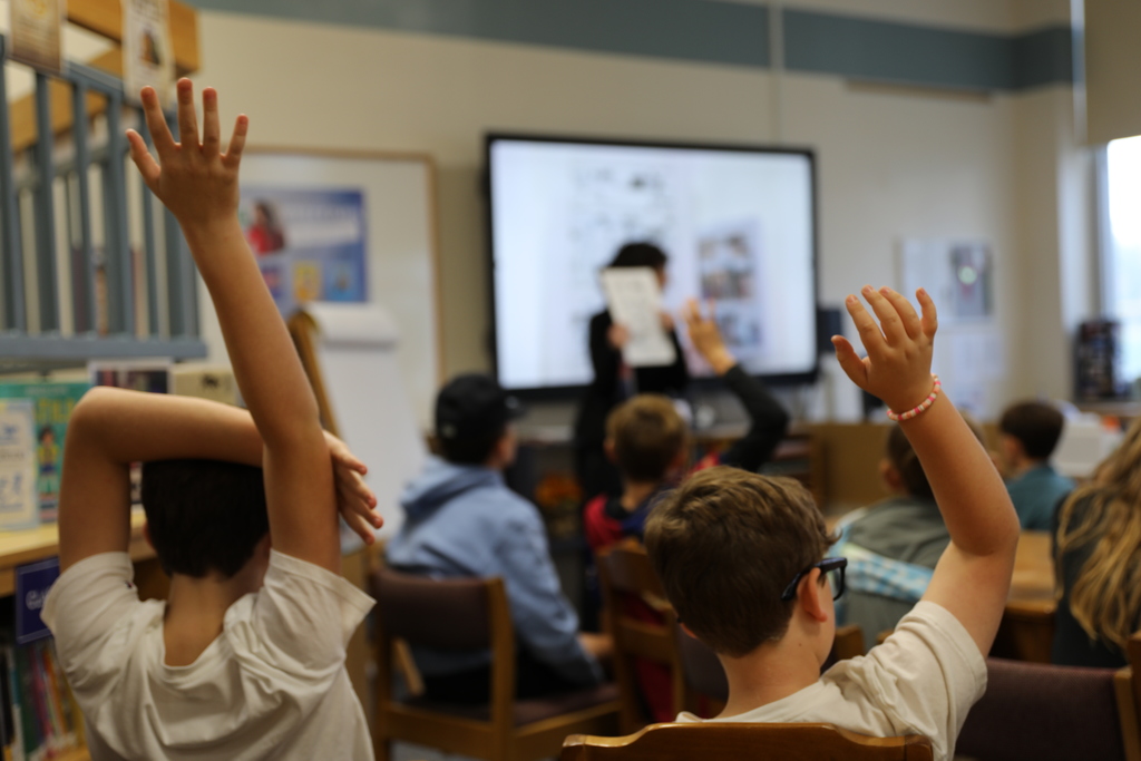 two students raising their hands to ask about the book