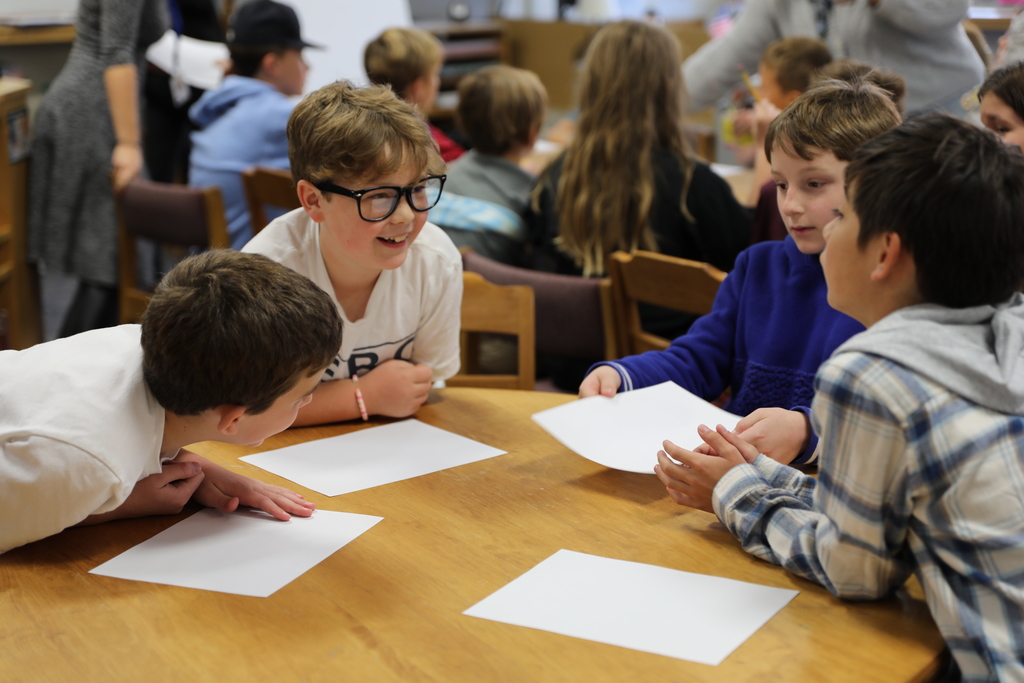 four students laughing together while working on drawings