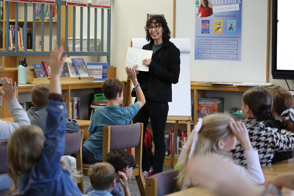 an author showing her book open faced to the class