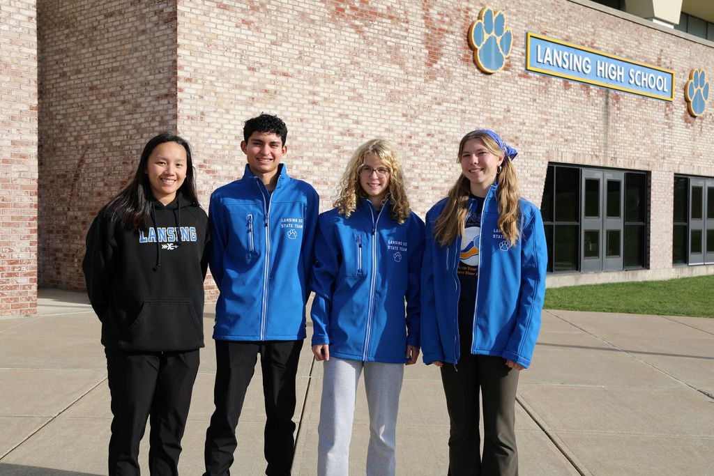 3 students and a coach pose for picture outside the school