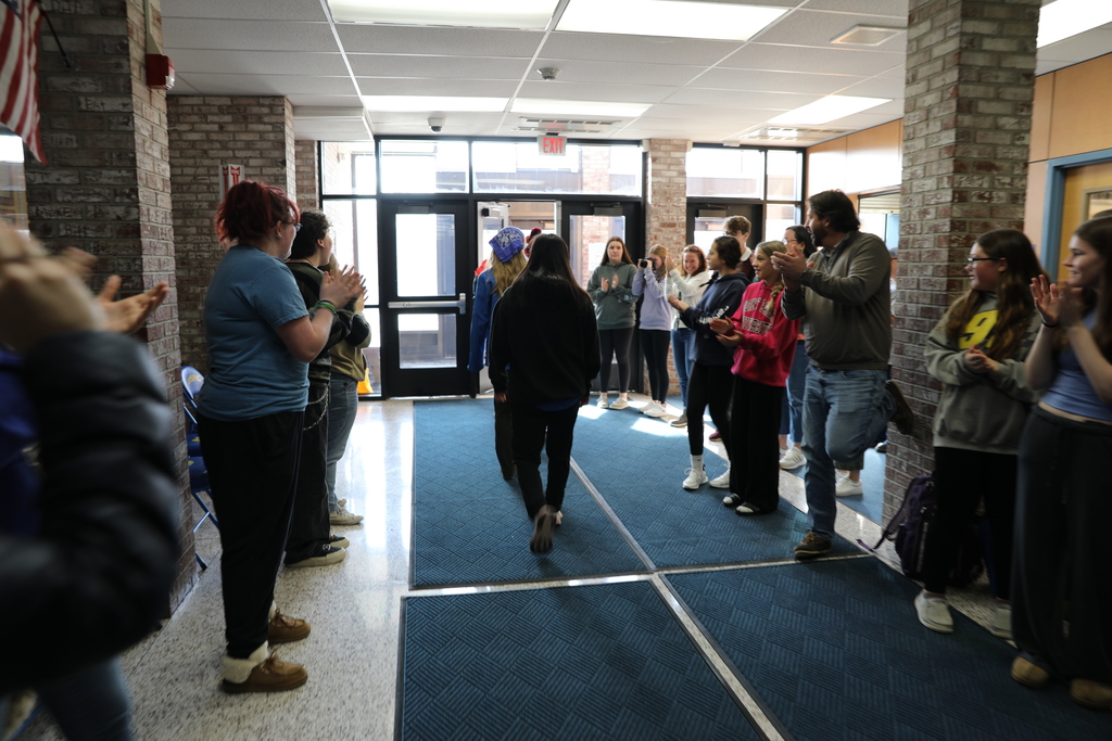 large group of staff and students cheer on the athlete students as they leave