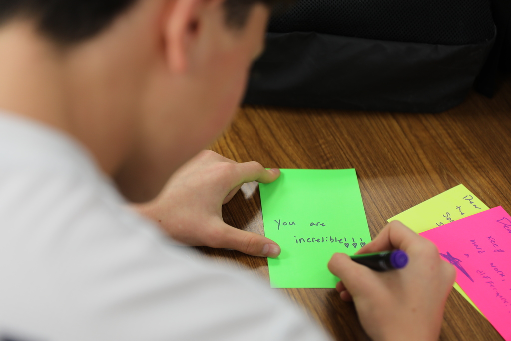 a student writing a note that says "you are incredible"