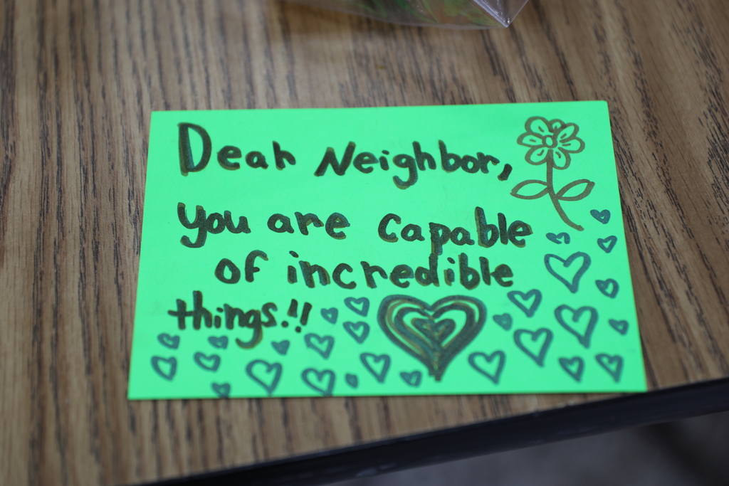 a close up of a note card which reads "Dear neighbor, you are capable of incredible things"