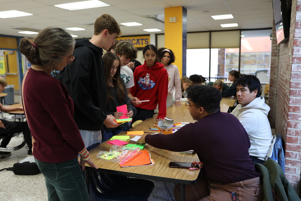 students gathering around the reception desk to collect notecards