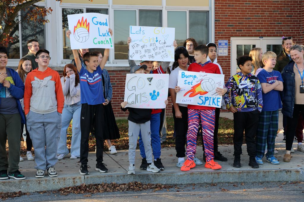 middle school students holding up signs to celebrate the volleyball team
