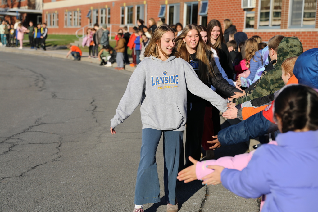 the volleyball team walking by the Elementary School and giving highfives