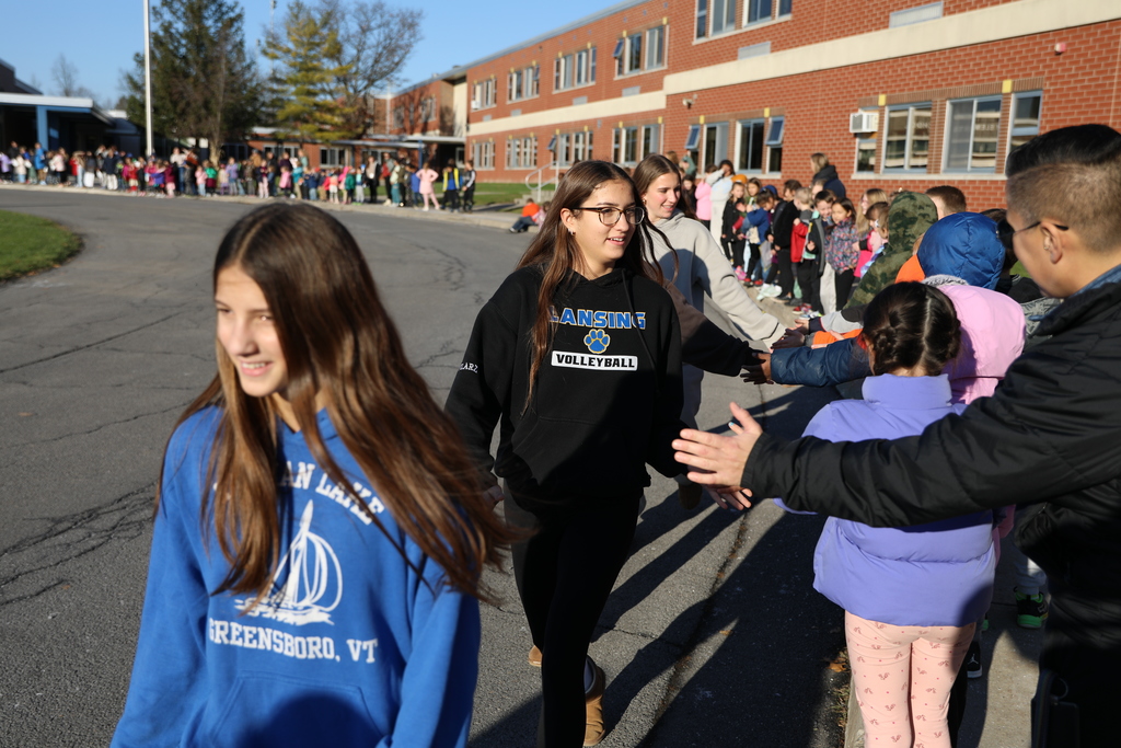 the volleyball team walking by the Elementary School and giving highfives